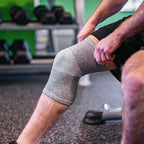 Person wearing a gray knee brace in a gym setting